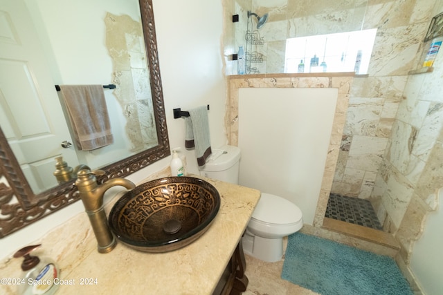 bathroom with vanity, toilet, and tiled shower