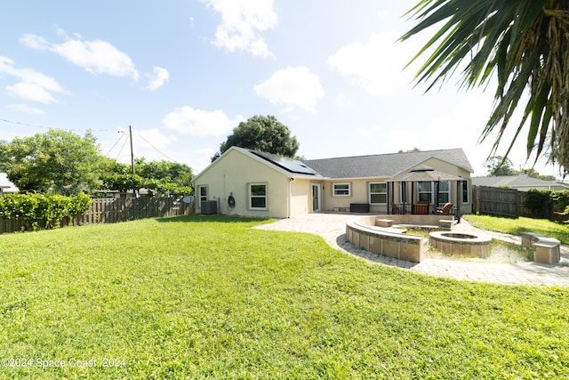 rear view of property with a lawn, a patio, an outdoor fire pit, and central AC unit