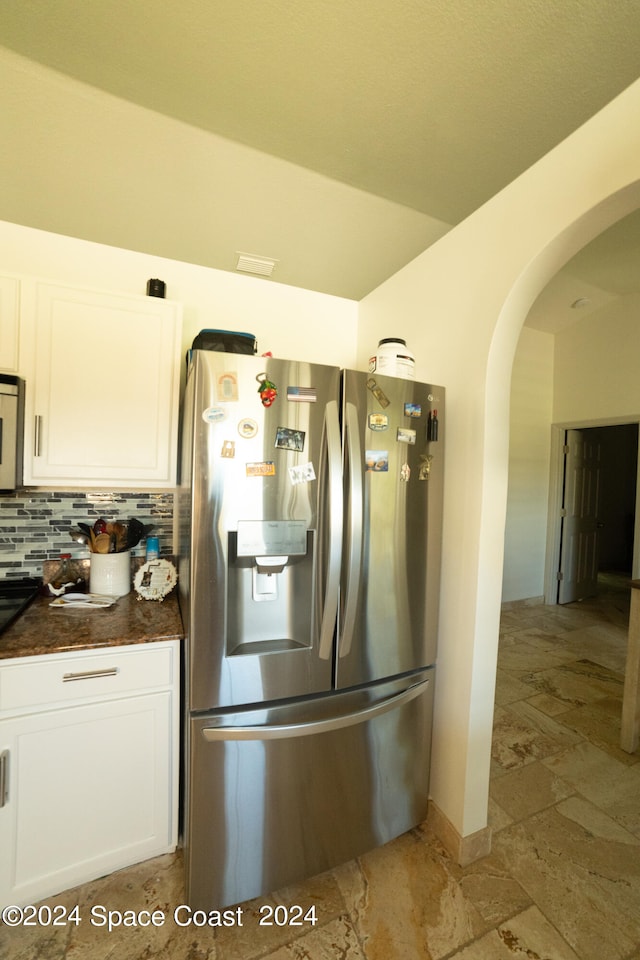 kitchen with stainless steel fridge, backsplash, and white cabinets