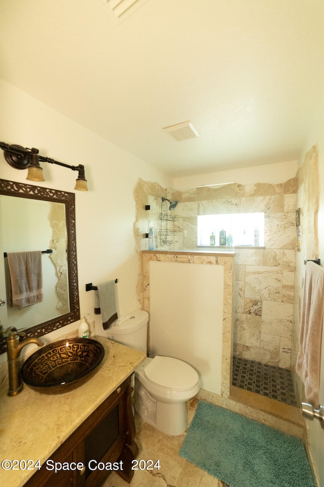 bathroom with tile patterned floors, tiled shower, toilet, and vanity