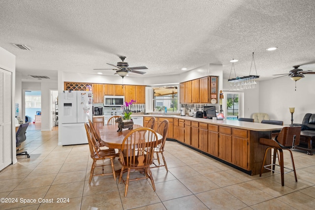 kitchen with white appliances, ceiling fan, a healthy amount of sunlight, and a textured ceiling