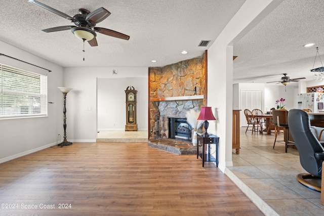 living room featuring a textured ceiling, a fireplace, hardwood / wood-style floors, and ceiling fan