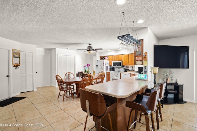 tiled dining room with a textured ceiling and ceiling fan