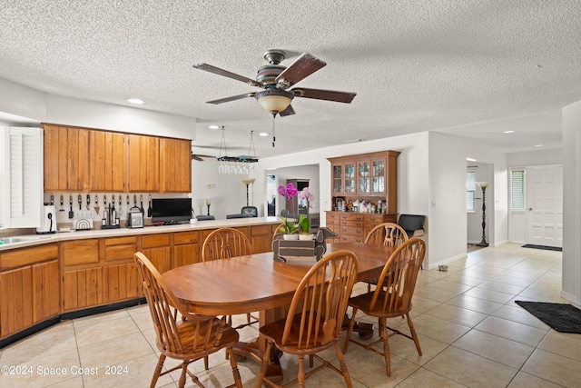 tiled dining space with ceiling fan, sink, and a textured ceiling