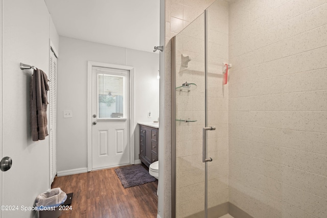 bathroom featuring hardwood / wood-style floors, a shower with shower door, vanity, and toilet