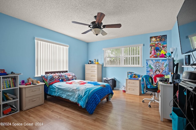 bedroom featuring light wood-type flooring, ceiling fan, and a textured ceiling