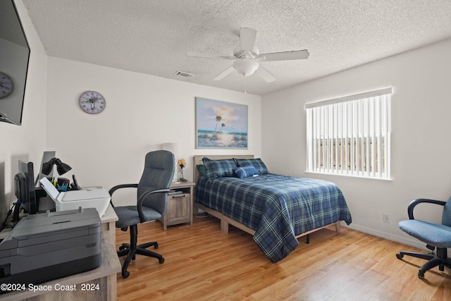 bedroom with light wood-type flooring, a textured ceiling, and ceiling fan