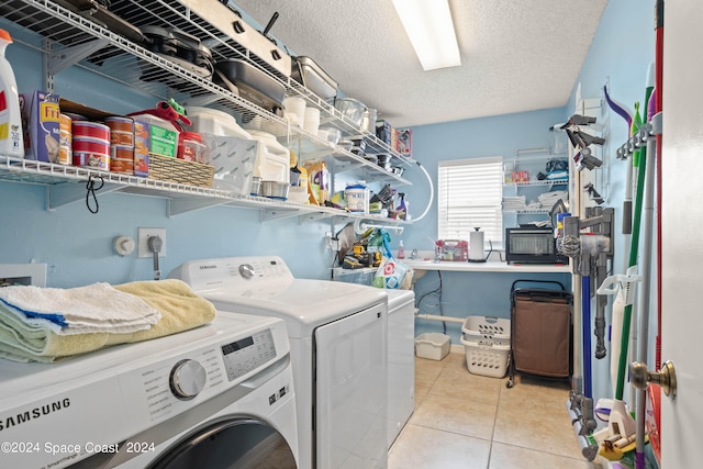 clothes washing area with light tile patterned floors, washer and clothes dryer, and a textured ceiling