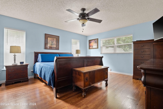 bedroom with ceiling fan, a textured ceiling, and light hardwood / wood-style flooring