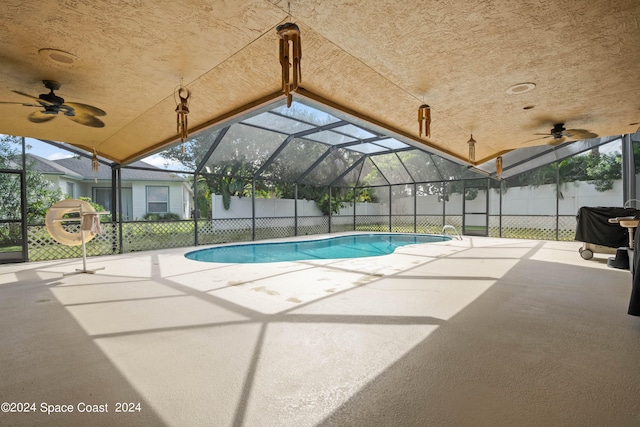 view of pool with glass enclosure, ceiling fan, and a patio area