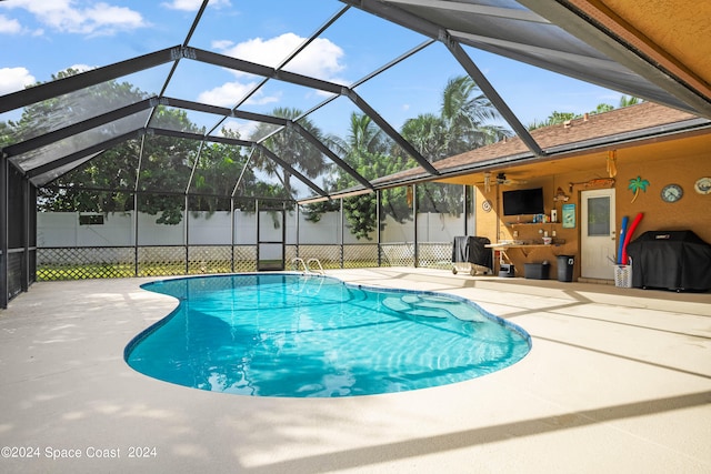 view of pool with glass enclosure, ceiling fan, and a patio area