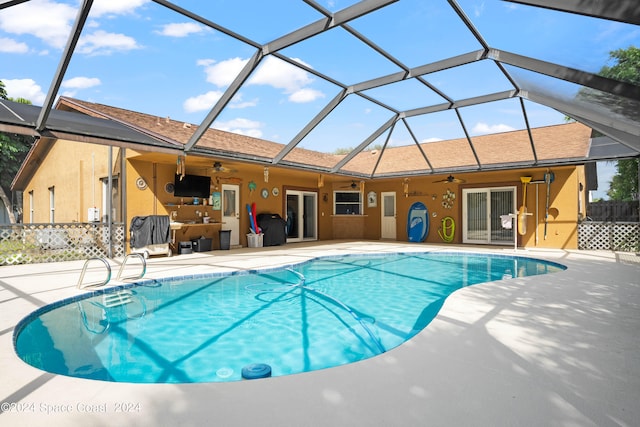 view of swimming pool with glass enclosure, ceiling fan, and a patio area