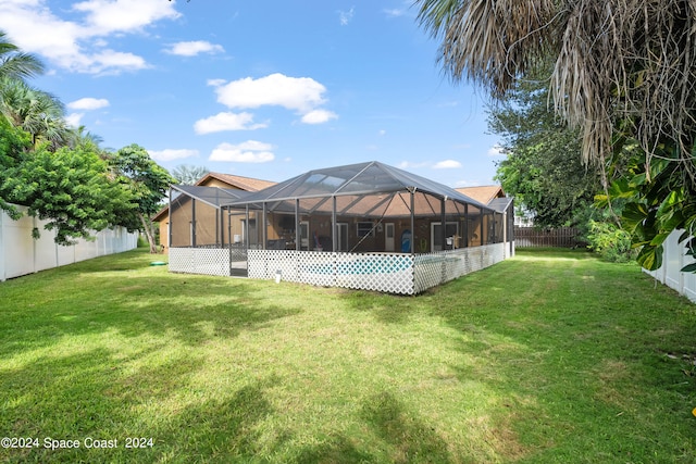 rear view of house featuring glass enclosure and a yard