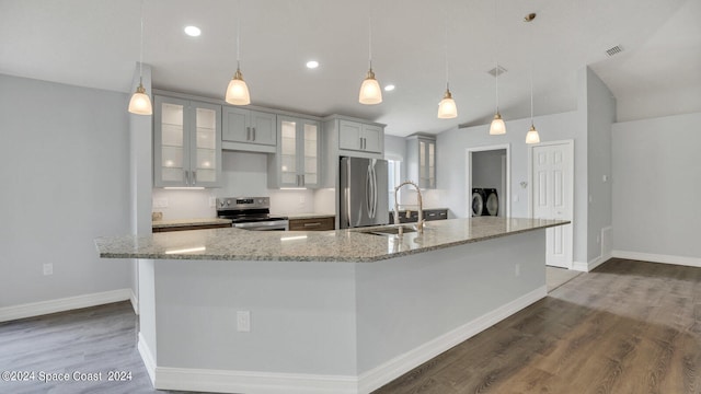 kitchen with decorative light fixtures, dark wood-type flooring, stainless steel appliances, sink, and a large island