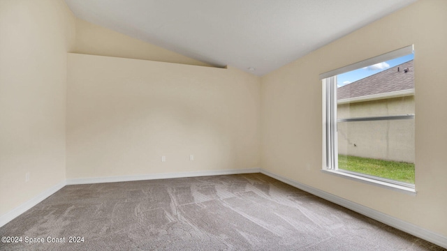 carpeted spare room featuring lofted ceiling