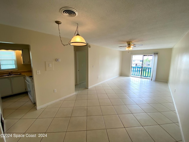 tiled empty room featuring a textured ceiling, sink, and ceiling fan