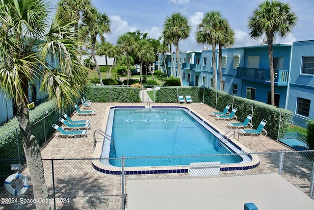 community pool with a patio area and fence