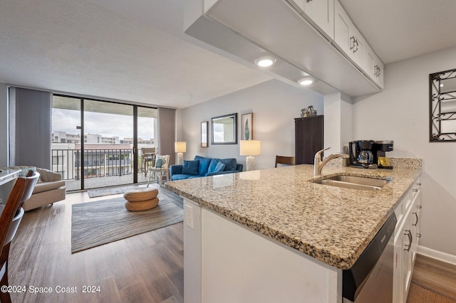 kitchen with sink, dishwasher, light stone countertops, dark hardwood / wood-style floors, and white cabinetry