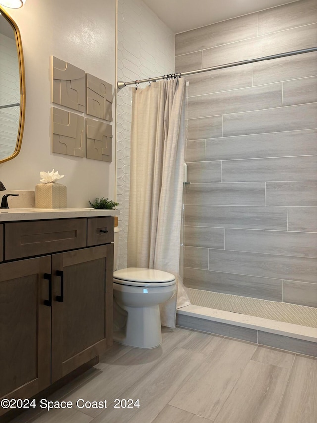 bathroom featuring curtained shower, toilet, hardwood / wood-style flooring, and vanity