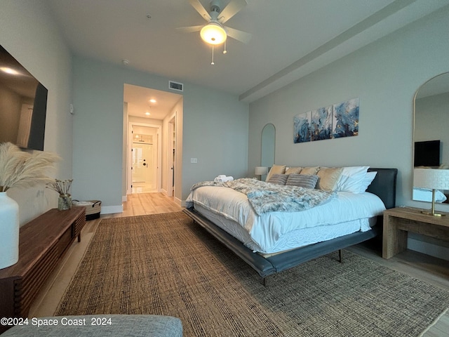 bedroom with ceiling fan, hardwood / wood-style flooring, and connected bathroom