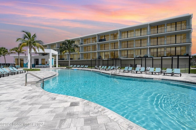 pool at dusk featuring a patio