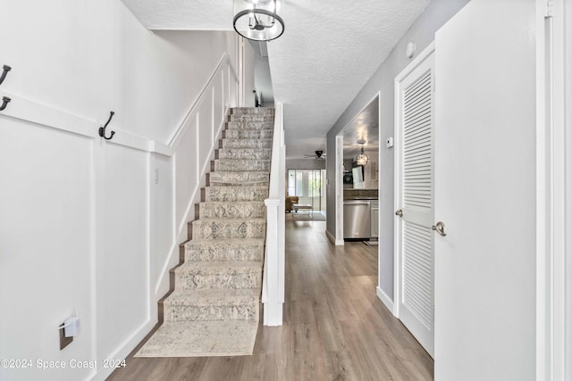 stairs with a textured ceiling, hardwood / wood-style flooring, and ceiling fan