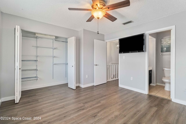 unfurnished bedroom with ensuite bathroom, wood-type flooring, and a textured ceiling