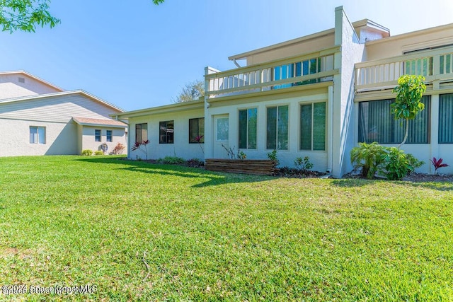 back of house with a yard and a balcony