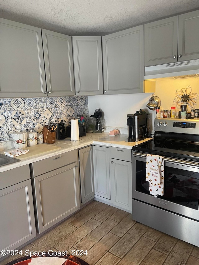 kitchen with a textured ceiling, light hardwood / wood-style flooring, range with two ovens, and gray cabinetry