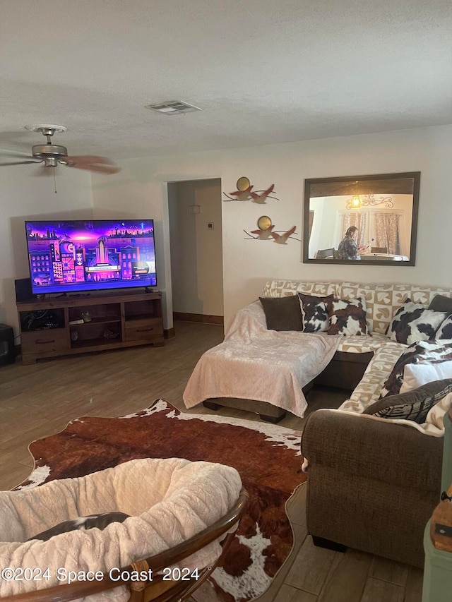 living room featuring a textured ceiling, hardwood / wood-style flooring, and ceiling fan