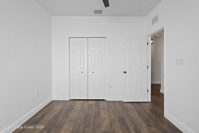 unfurnished bedroom featuring dark wood-type flooring, ceiling fan, and a closet