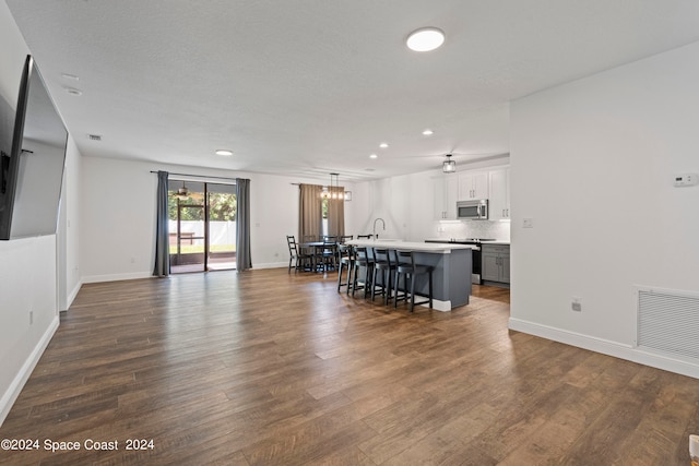 living room featuring dark wood-type flooring, a textured ceiling, sink, and a notable chandelier