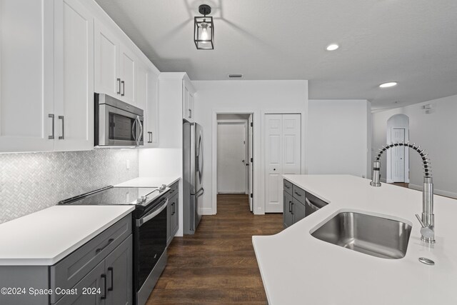 kitchen featuring dark hardwood / wood-style flooring, an island with sink, stainless steel appliances, sink, and white cabinets