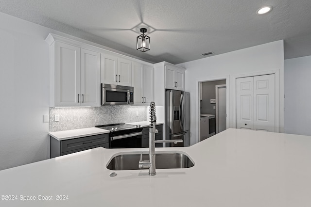 kitchen featuring white cabinetry, a textured ceiling, stainless steel appliances, sink, and decorative backsplash