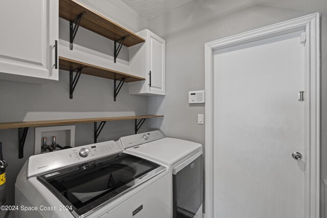 clothes washing area featuring a textured ceiling, cabinets, and washing machine and dryer