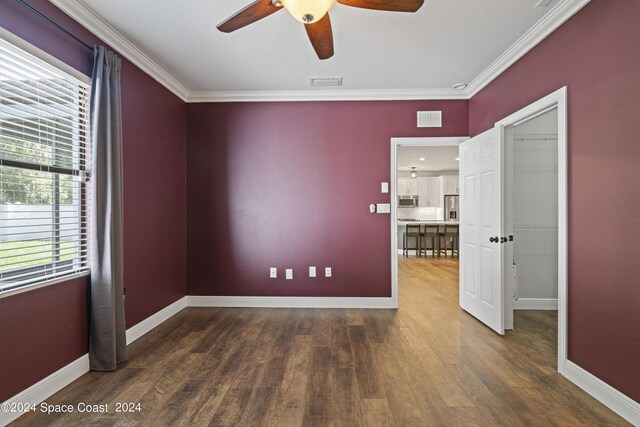 empty room with crown molding, dark hardwood / wood-style flooring, and ceiling fan