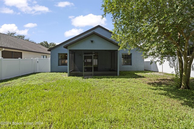 rear view of property featuring a sunroom and a yard