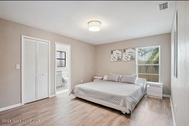 bedroom with light hardwood / wood-style flooring and ensuite bath