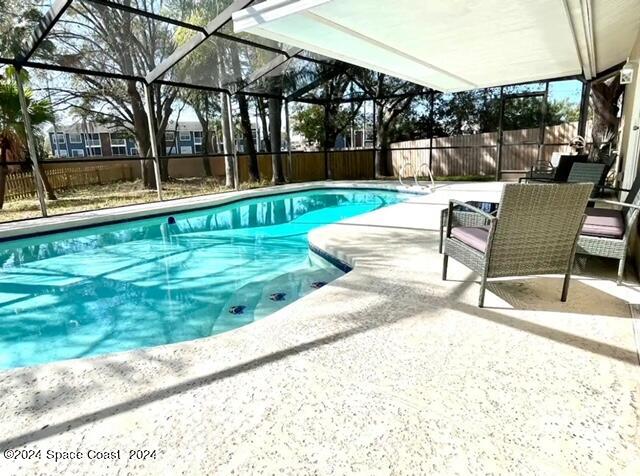 view of pool with a patio area and glass enclosure