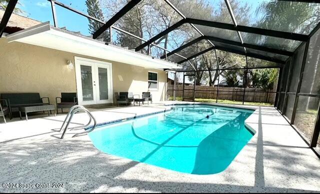 view of swimming pool featuring a lanai, a patio area, and french doors