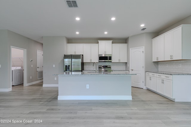 kitchen with washer / clothes dryer, light hardwood / wood-style floors, stainless steel appliances, and a kitchen island with sink