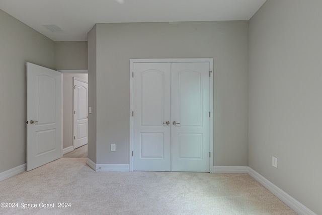 unfurnished bedroom with light colored carpet and a closet