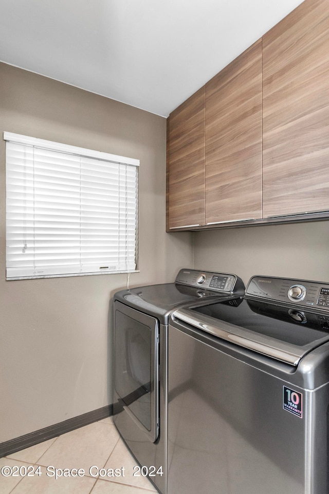 laundry room with light tile patterned floors, cabinets, and independent washer and dryer