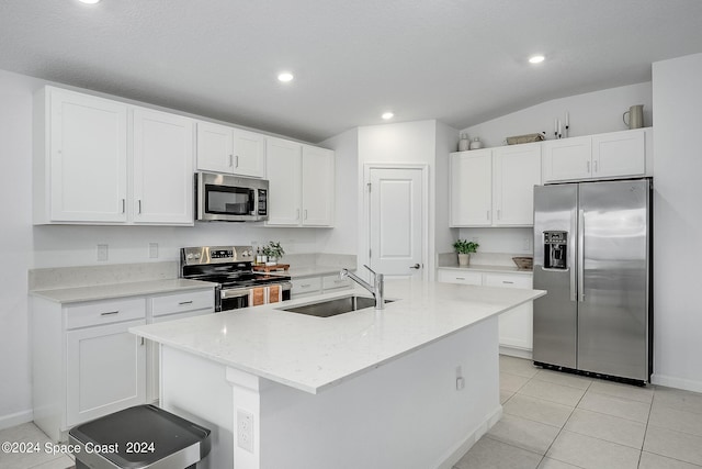 kitchen with a center island with sink, appliances with stainless steel finishes, sink, lofted ceiling, and white cabinets