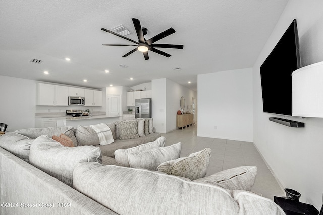 living room featuring a textured ceiling, light tile patterned floors, and ceiling fan