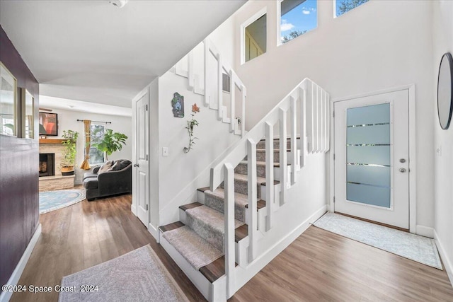 stairs featuring wood-type flooring and a stone fireplace