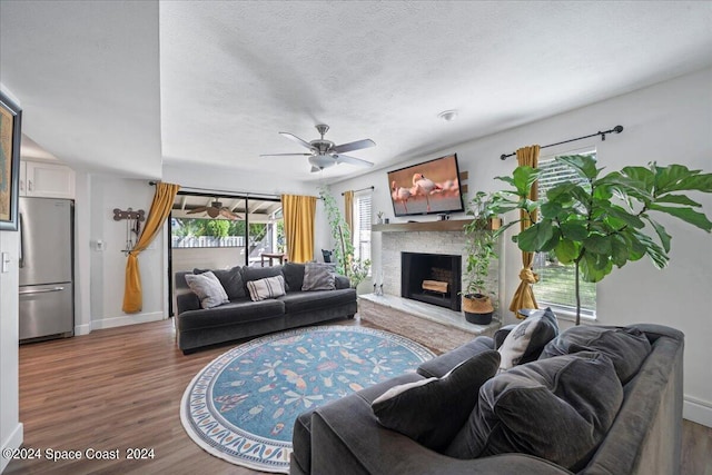 living room with a textured ceiling, dark wood-type flooring, and ceiling fan