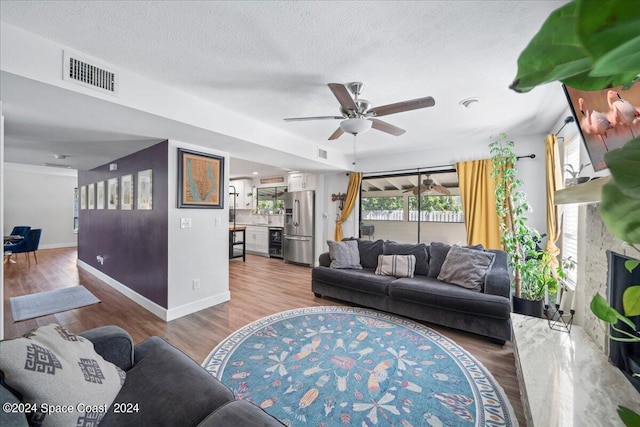 living room featuring beverage cooler, hardwood / wood-style floors, ceiling fan, and a textured ceiling