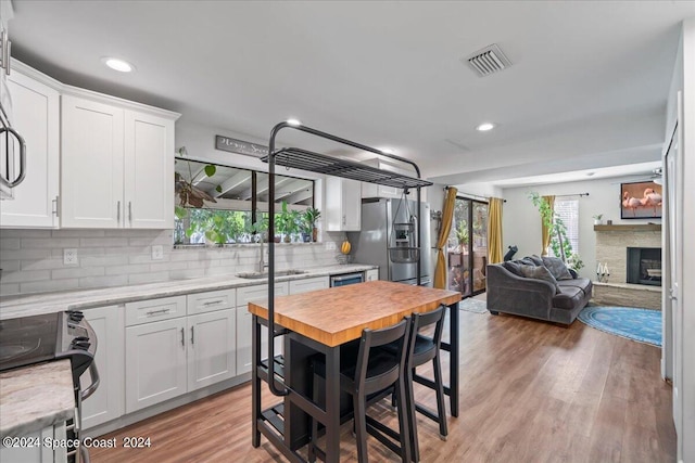 kitchen with stainless steel fridge with ice dispenser, white cabinetry, and plenty of natural light