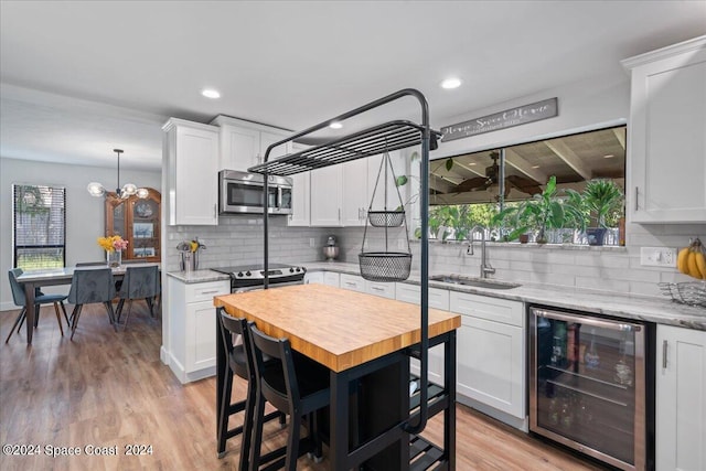 kitchen with wine cooler, sink, appliances with stainless steel finishes, and white cabinets